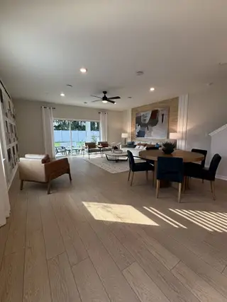 A modern open-concept living space with wood-look flooring, stylish furniture, and sleek lighting in Emerald Pointe by Pulte Homes (Apopka, FL).