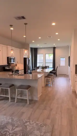 Model Home A modern kitchen and dining space with granite countertops, pendant lighting, and wood-look flooring.