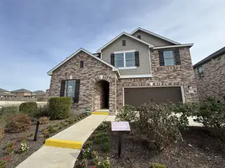 Model Home A two-story brick and siding home in Salerno by KB Home (Round Rock, TX), from the Classic Collection, features a well-defined walkway and landscaped front yard.
