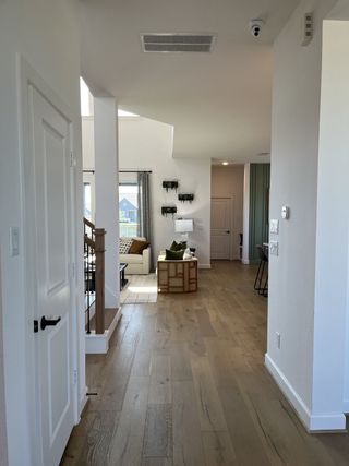 A modern hallway with elegant wooden floors leading to a cozy living area, featuring stylish furniture and soft lighting.
