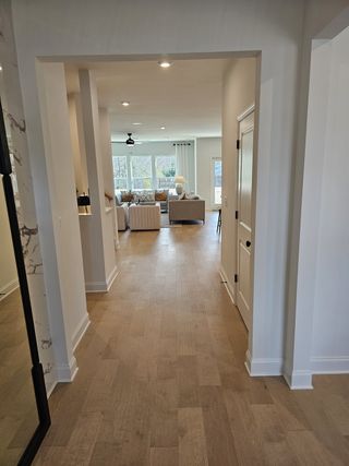 Model Home An inviting hallway leads to a cozy, sunlit living area with stylish furnishings and warm wood floors.