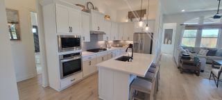 Model Home A spacious kitchen with modern appliances and an open-plan living area featuring natural light in Veranda by Brightland Homes.