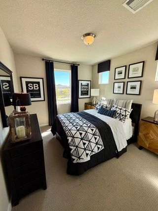 A cozy bedroom featuring a chic black and white bedspread, wall art, and ample natural light for a modern touch.