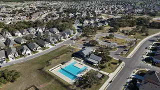 Community Amenities A stunning aerial view of 6 Creeks at Waterridge by Highland Homes, showcasing the community pool, park, and surrounding new homes (Kyle, TX).