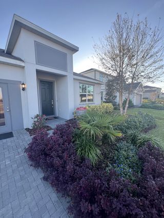 A beautifully landscaped modern home with lush greenery in Cypress Park Estates by Park Square Residential (Haines City, FL).