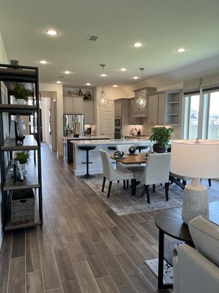 Model Home An open-plan kitchen and dining area with sleek cabinetry, pendant lighting, and wood-look flooring.