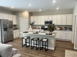 A modern kitchen with white cabinetry, granite countertops, stainless appliances, and a chic central island.