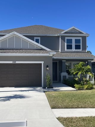 Street view A charming two-story gray home with manicured landscaping in Veranda Oaks by Taylor Morrison (Port St. Lucie, FL).