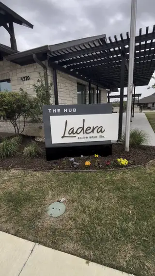 Street view A modern community entrance with sleek stone facade and landscaped greenery in Ladera Prosper by Ladera Texas (Prosper, TX).