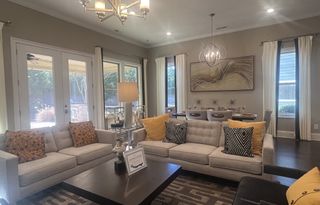 A cozy living-dining area with neutral tones, plush seating, abstract art, and ample natural light.
