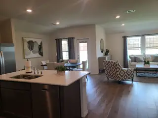 Model Home A modern open-plan living space with natural light, featuring a sleek kitchen island, stylish chairs, and contemporary decor.