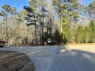 A serene wooded entrance to Watkins Glen by Exeter Building Company in Wake Forest, NC, with tall trees lining the road.