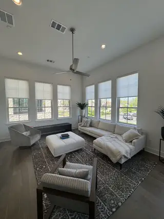 Model Home A bright living room with modern seating, large windows, and a stylish gray-patterned rug.