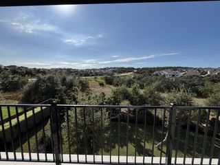 A scenic overlook from a balcony, showcasing a lush green landscape and the residential expanse of Provence by Drees Custom Homes in Austin, TX.