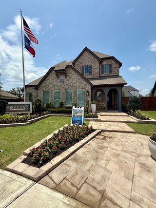 A charming brick home with lush landscaping and a welcoming path in Meridiana: 50ft. lots by Highland Homes (Manvel, TX).