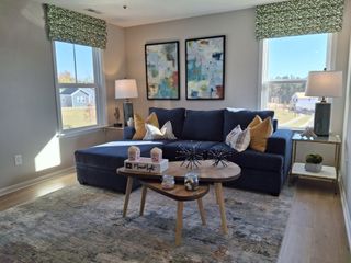 Model Home A cozy living room with a navy sectional, abstract artwork, and chic decor, filled with natural light and modern accents.