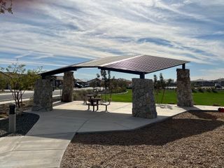 Community Amenities A quaint park pavilion with stone pillars and seating in IronWing at Windrose by Brightland Homes (Litchfield Park, AZ).
