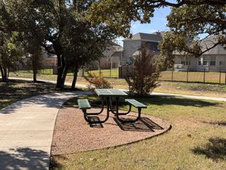 A picturesque park setting with picnic table and winding path in Highland Village by Coventry Homes (Georgetown, TX).