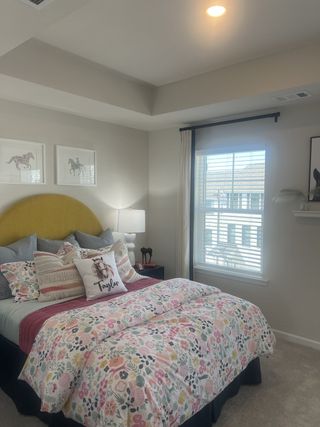 A cozy bedroom featuring floral bedding, horse-themed wall art, and a bright window for natural light.