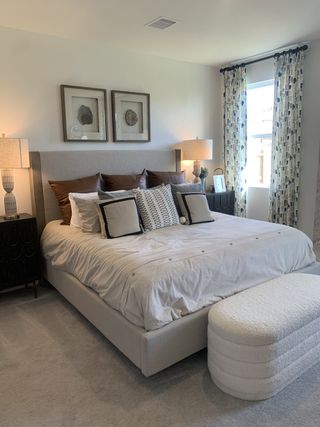 A cozy bedroom featuring a plush bed, elegant lamps, and patterned curtains for a serene atmosphere.