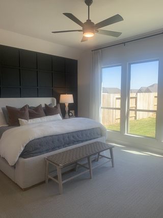 A cozy bedroom with a statement black accent wall, plush bedding, and large windows inviting natural light.