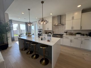 A sleek kitchen with a large island, modern pendant lights, and floor-to-ceiling windows opening to a lush backyard.