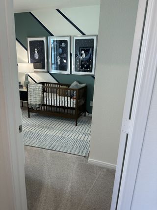 A cozy nursery with a wooden crib, playful artwork, and a striped rug, creating a serene and inviting atmosphere.
