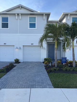 A charming white townhouse with palm trees and brick driveway in Veranda Landing by Lennar (Port St. Lucie, FL).