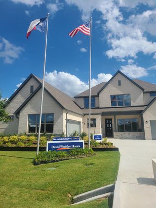 Model Home Elegant white brick home with manicured lawn in Northshore at Lakewood Village by David Weekley Homes (Lakewood Village, TX).