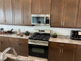 A modern kitchen with sleek wood cabinets, a stainless steel oven, and a marbled countertop for a stylish cooking space.