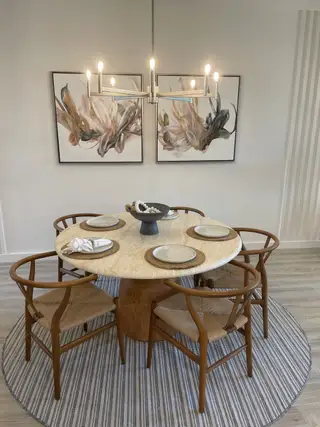A cozy dining area with a round wooden table, modern chandelier, and abstract artwork on the walls.