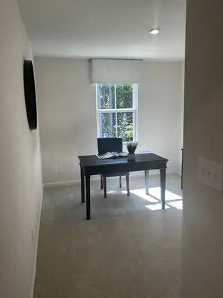 Model Home A bright home office with a sleek desk, plush carpet, and a window view.