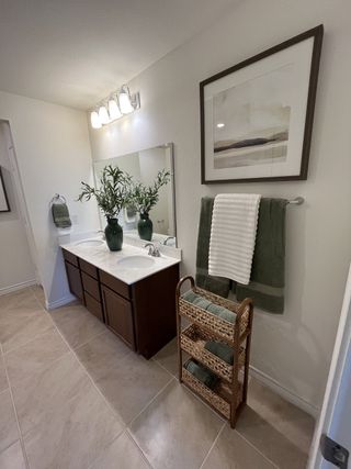 Model Home A spacious bathroom with a dual vanity, elegant dark wood cabinetry, and bright lighting, creating a sophisticated and relaxing space.