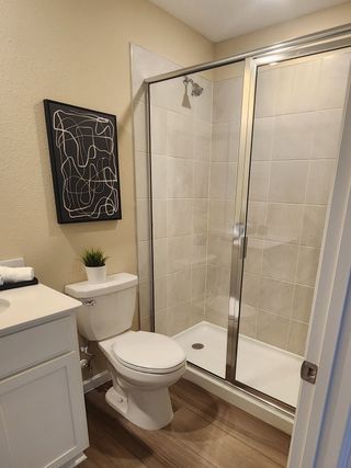 Model Home A chic bathroom with a glass-enclosed shower, modern tile, wood flooring, and elegant decor for a stylish look.