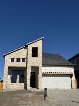 Street view A modern stone and siding home with a unique roofline in Cedar Brook by M/I Homes (Leander, TX).