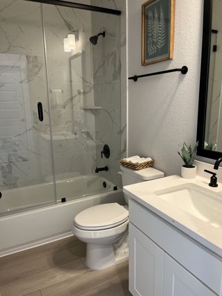 Model Home A modern bathroom with a marble-tiled shower, sleek black fixtures, and contemporary decor accents.