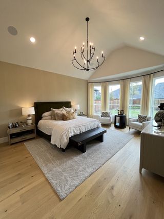 An elegant bedroom featuring a cozy bed, modern chandelier, and large windows with soft drapes, creating a serene retreat.
