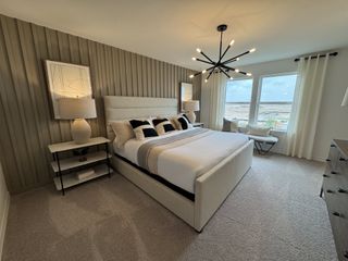 A modern bedroom featuring a textured accent wall, sleek lighting, and large windows with natural light.