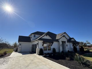 Street view A striking modern farmhouse with stone accents and dark trim in North Haven by GFO Home (Liberty Hill, TX).