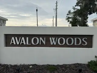 Community entrance sign amidst trees in Avalon Woods by D.R. Horton (Newberry, FL).
