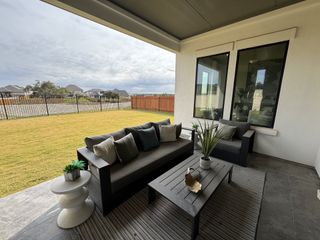 Model Home A cozy patio with modern outdoor furniture, neutral cushions, and a view of a landscaped backyard and neighboring houses.