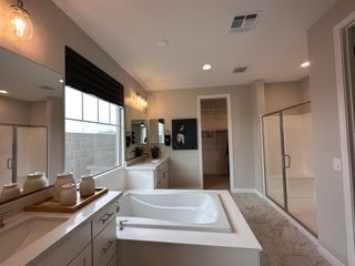 A spacious bathroom with a luxurious soaking tub, sleek double vanity, and glass-enclosed shower.