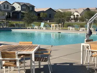 A beautiful community pool area with modern lounge chairs and tables in Los Cielos at Rancho Mercado by Taylor Morrison (Surprise, AZ).
