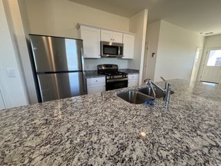 A modern kitchen with sleek granite countertops, stainless steel appliances, and bright white cabinets.