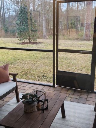 A cozy screened-in patio with comfortable seating and scenic backyard views, perfect for relaxation and outdoor entertaining.