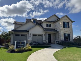 Street view A modern two-story stone and stucco home in Parmer Ranch 60′ by Sitterle Homes, featuring a manicured lawn (Georgetown, TX).