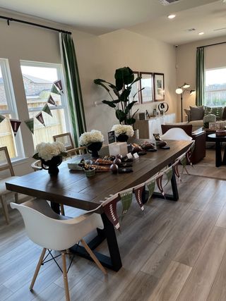 A modern dining room with festive decor, featuring a rustic table, elegant chairs, and lush greenery for a cozy gathering.
