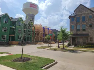New construction and completed homes in Wade Settlement by Megatel Homes, Frisco, TX, with a prominent water tower nearby.