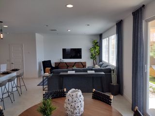 Contemporary open-plan living area with a cozy sectional, chic dining space, and natural light through large windows.