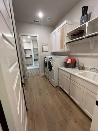 A spacious laundry room with sleek cabinetry, hardwood floors, and modern appliances.